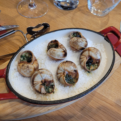 Plat de coquilles Saint-Jacques gratinées, servi dans une poêle en fonte au restaurant Le Cathédrale Brasserie à Chartres. Cuisine française raffinée.