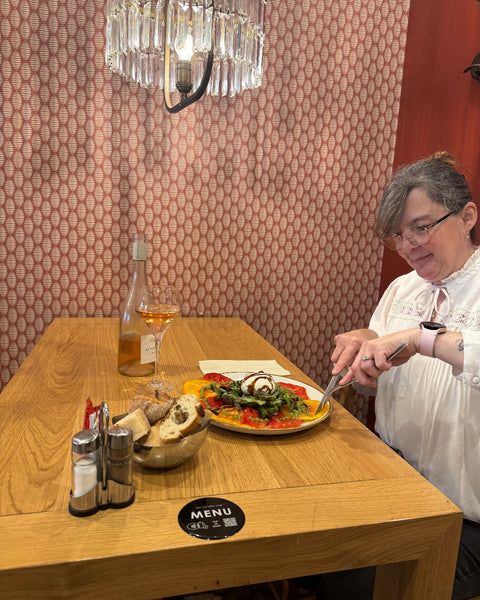Cliente savourant une burrata aux tomates anciennes à la Brasserie Le Cathédrale Gourmand à Chartres, accompagnée de pain maison et d’un verre de rosé, dans une atmosphère cosy.