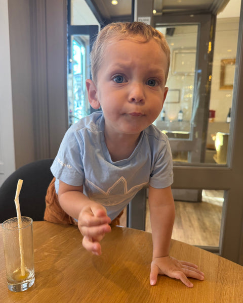 Enfant curieux et expressif à table à la Brasserie Le Cathédrale Gourmand à Chartres, ambiance familiale et détendue autour d’un jus de fruits terminé.