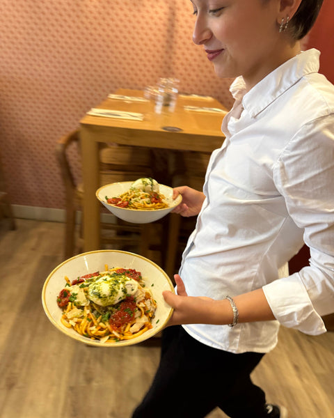 Serveuse concentrée à la Brasserie Le Cathédrale à Chartres, apportant deux assiettes généreuses de plats faits maison dans une ambiance chaleureuse.