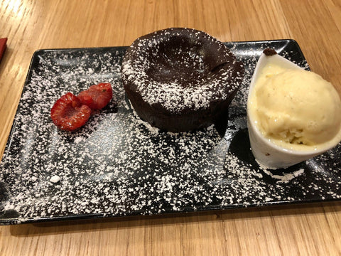 Fondant au chocolat servi avec une boule de glace et une garniture de framboises, présenté sur une assiette élégante