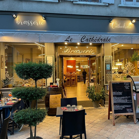 Entrée de Le Cathédrale Brasserie à Chartres, mettant en valeur son charme français traditionnel avec des plantes décoratives et un menu accueillant.