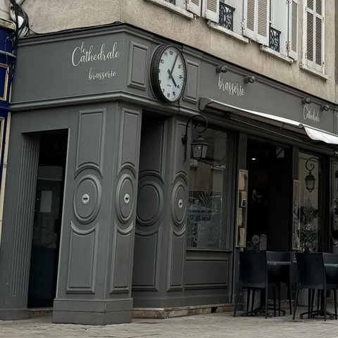 Façade élégante de Le Cathédrale Brasserie à Chartres, avec des détails architecturaux classiques et une horloge distinctive.