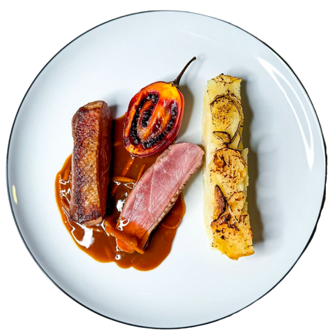 Magret de canard rosé accompagné d’une tomate grillée, d’une sauce riche et d’un gratin dauphinois aromatisé au romarin, servi à la brasserie Le Cathédrale à Chartres.