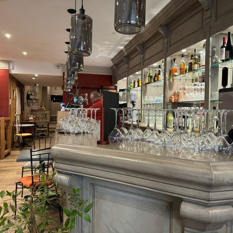 Bar élégant et accueillant de Le Cathédrale Brasserie à Chartres, avec une sélection de verres à vin et des lumières suspendues modernes.