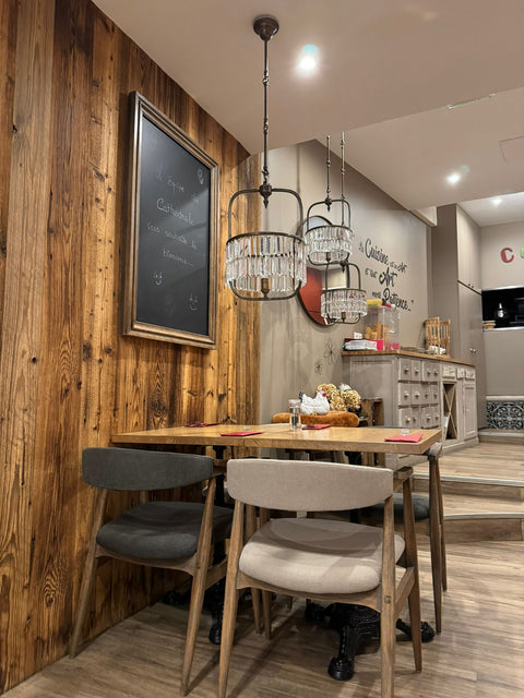 Coin intime avec table et chaises élégantes à Le Cathédrale Brasserie, mettant en valeur un décor en bois chaleureux et un tableau noir inscrit de messages de bienvenue.